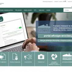 Ręce piszące na laptopie, na ekranie którego widać portal beneficjenta i przycisk "Sprawdź status wniosku".