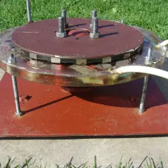 Domowa turbina wodna z magnesami i przewodami, zamontowana na podstawie.